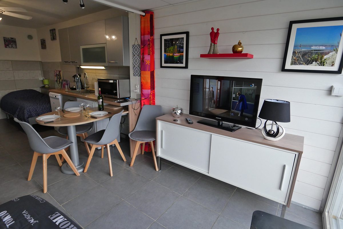 Séjour avec télévision, buffet de rangement et table de repas