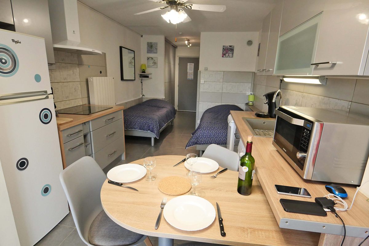 Le studio vu depuis la table de repas&nbsp;: cuisine équipée et deux lits de 90&nbsp;cm